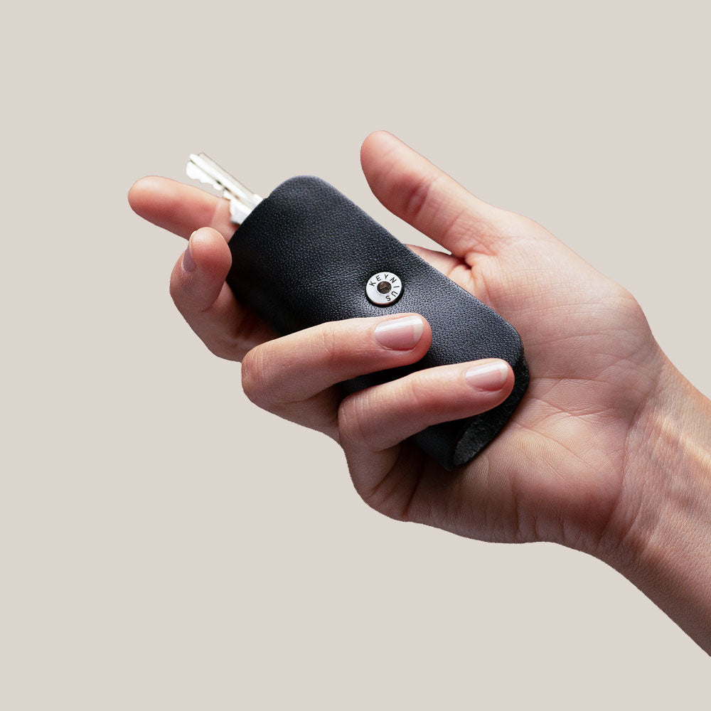 Hand holding a black leather key organizer